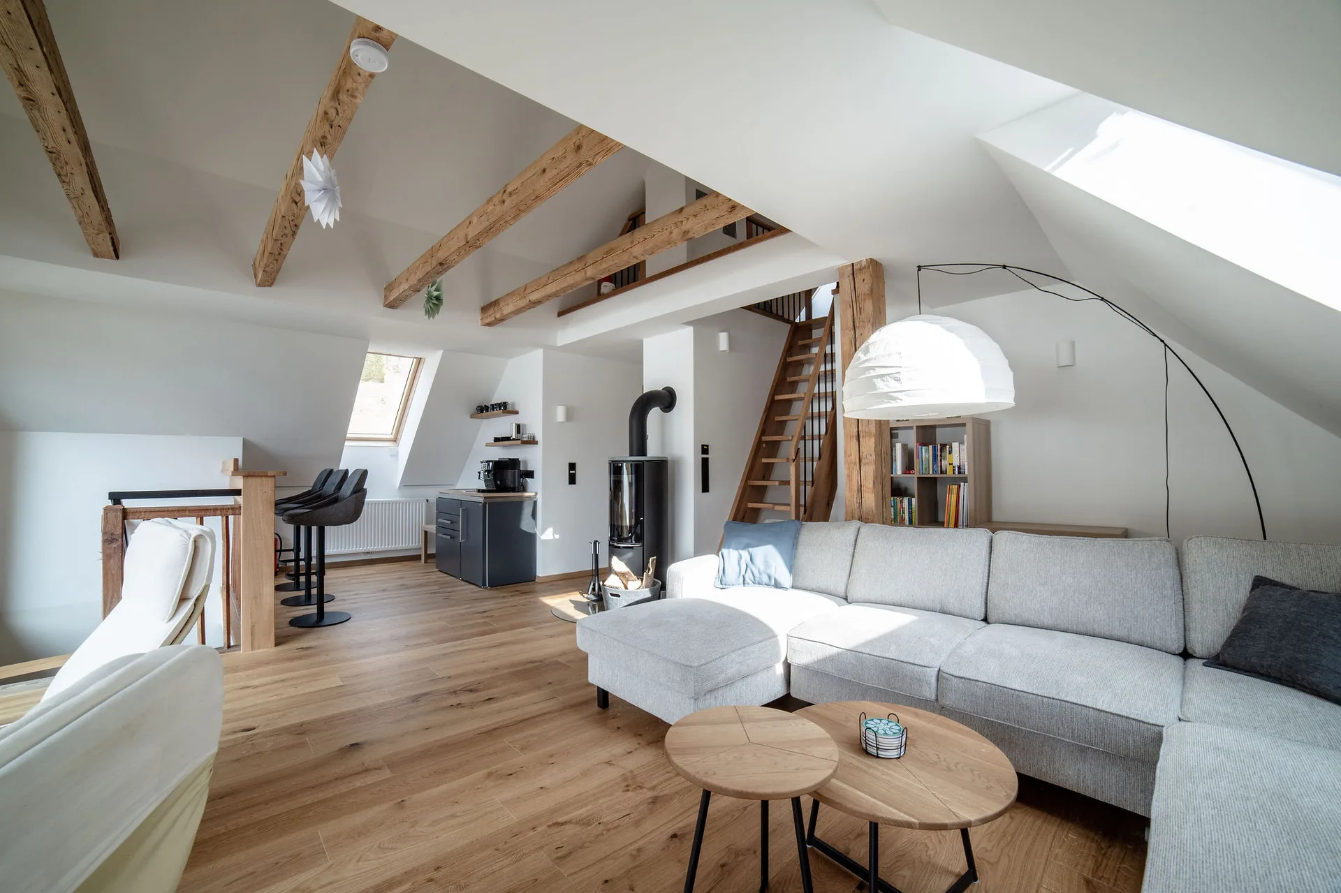 Wohnzimmer im Dachgeschoss mit Kaminofen, Teeküche und Panoramafenster mit Bergblick.